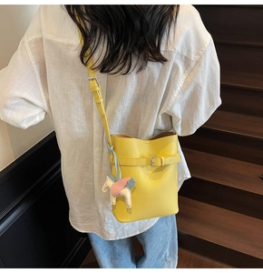 Close-up of yellow litchi texture bucket bag with Pegasus charm on a model