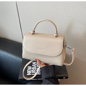 Close-up of cream leather shoulder bag showing lychee grain texture and metal hardware