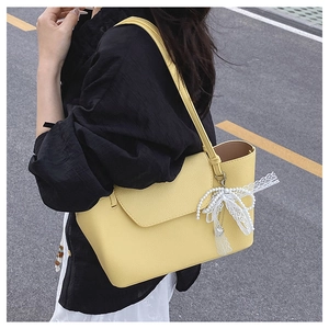 Detail of yellow pebbled leather tote with pearl and lace butterfly charms on side