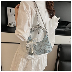 Detail of light blue denim handbag with silver ruched handle and pearl bow charm