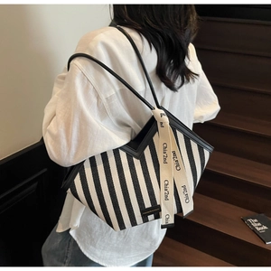 Detail of black and white striped canvas tote with V-shaped opening and leather straps