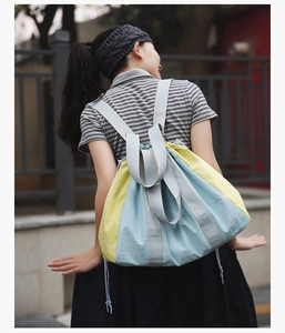 Detail of a large capacity drawstring backpack in yellow and blue color-blocking design