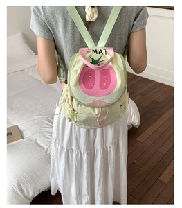 Detail view of cream green canvas backpack with tomato motif and MAT logo detail