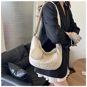 Close-up of beige quilted dumpling bag texture and mini coin purse worn by model