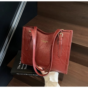 Close-up of brick red tote bag with vintage leather texture and gold buckle detail
