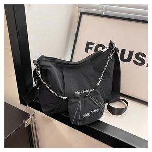 Detail of black canvas tote bag and mini pouch with Happy Sunday print and metal chain