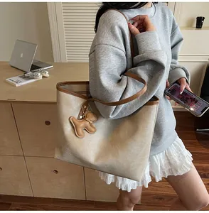 Detail of beige crocodile pattern tote bag with dog charm and smile print for work