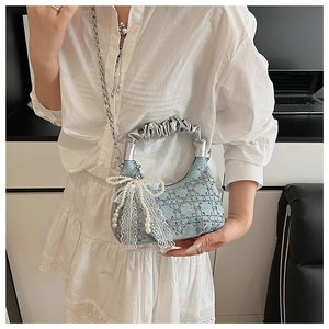 Detail of light blue denim handbag featuring a lace bow and pearl tassels with silver chain