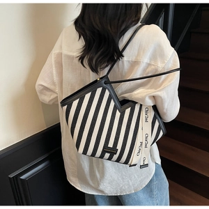 Detail of black and white striped canvas tote with V-cut top and side letter webbing