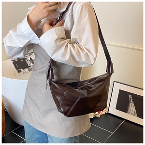 Détail d'un sac hobo marron foncé en cuir brillant avec des accessoires en métal argenté