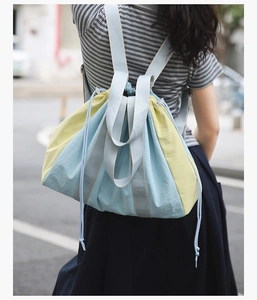Outdoor shot of a blue and yellow drawstring backpack with nylon texture on a model