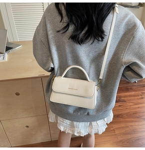 Detail view of cream leather crossbody bag with gold Fashion & Bags lettering on flap