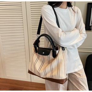 Close-up of cream canvas tote bag with brown stripes and leather reinforced bottom base