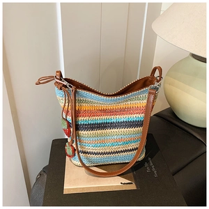 Close-up of vibrant multi-color woven straw bucket bag with red strawberry charms