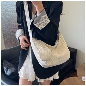 Detailed side view of off-white pleated crescent crossbody bag with round coin purse