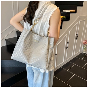 Gros plan du sac cabas gris clair avec motif gaufré et bandoulière chaîne dorée