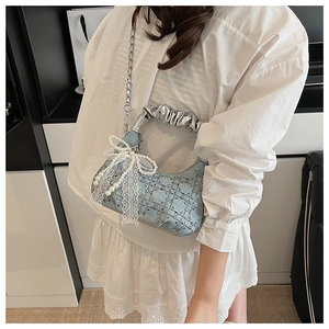 Detail of light blue denim handbag featuring pearl lace bow and silver chain strap