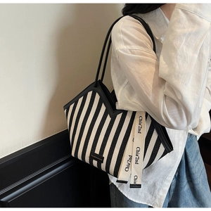 Detail of striped canvas tote with black leather straps and woven decorative ribbon