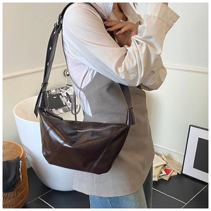 Détail du sac bandoulière en cuir brillant marron foncé avec large sangle et zip argenté