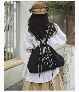 Outdoor shot showing back view of large black canvas drawstring tote bag with contrast stitching