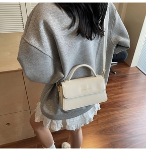 Detail of cream crossbody bag with gold FASHION & BAGS lettering and top handle