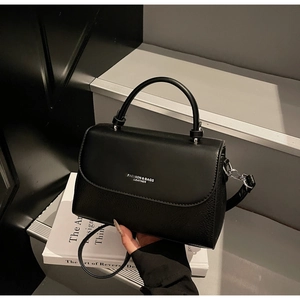 Close-up of black crossbody bag showing litchi leather texture and silver branding