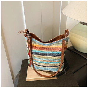 Detail of colorful woven shoulder bag with rainbow stripes and strawberry charms