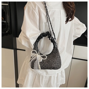Detail of tweed crossbody bag with ruched handle, lace bow, and pearl charm