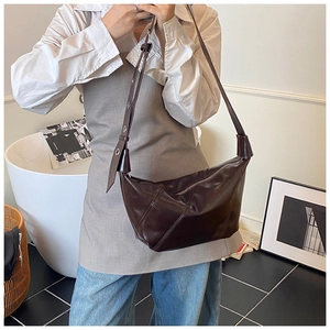 Gros plan du sac croissant marron foncé montrant le cuir synthétique brillant