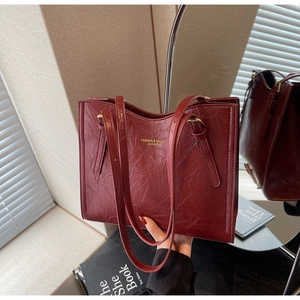 Detail of vintage burgundy tote bag with wrinkled leather texture and gold lettering