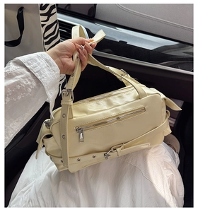 Detail of a creamy beige Boston bag showing silver zippers and synthetic leather texture
