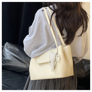Detail of cream white lychee leather tote bag with pearl lace pendant and double straps