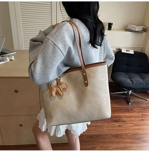 Detail of crocodile embossed tote bag with cute dog charm and brown shoulder straps