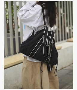 Detailed view of large black tote bag with white contrast drawstring and strap