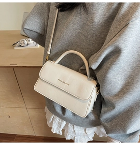 Side view of cream white crossbody bag with FASHION & BAGS lettering and top handle