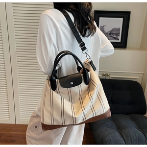 Detail of striped canvas tote bag with reinforced leather base and NOCO logo branding