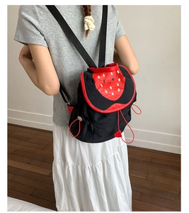 Detail of cute strawberry design backpack featuring red polka dots and cartoon expression