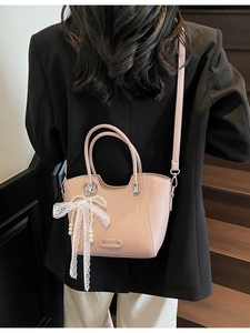 Sac cabas rose texture litchi avec nœud en dentelle blanche et pendentif perle sur modèle