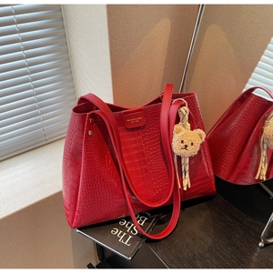 Close-up of red crocodile pattern tote bag with golden logo and cute plush bear charm