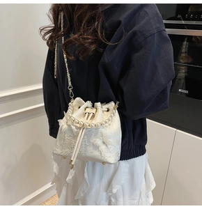 Detail of white lace bucket bag with pearl handle and delicate 3D bow decoration