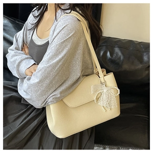 Detail of off-white tote bag with litchi grain texture and lace pearl bow accessory