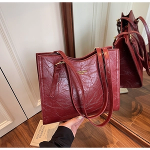 Macro detail of wine red tote bag showing vintage crinkled leather and gold embossed logo