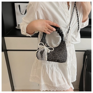Detail of tweed crossbody bag featuring pearl bow and delicate white lace accents