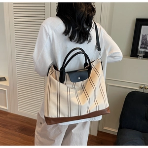 Detail of large striped tote bag with leather handles and removable black shoulder strap