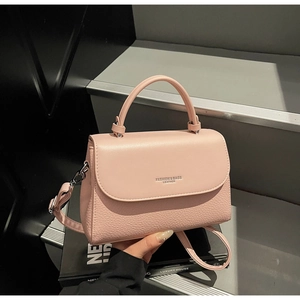 Detail of pink lychee leather handbag featuring Fashion & Bags logo and sturdy top handle