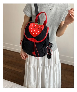 Detail showing the strawberry pattern and drawstring closure on the black canvas backpack