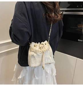 Detailed view of white jacquard bucket bag with pearl handle and golden chain strap