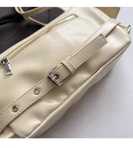 Detailed macro view of silver-toned zipper and adjustable leather strap on cream crossbody bag