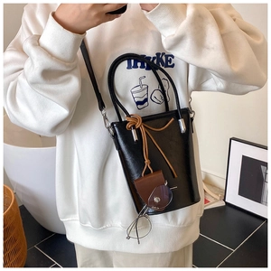 Detail of black leather bucket bag featuring a brown drawstring and matching glasses pouch