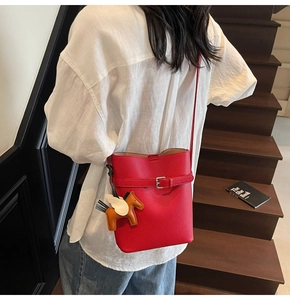 Red lychee pattern leather bucket bag with adjustable strap and decorative horse charm